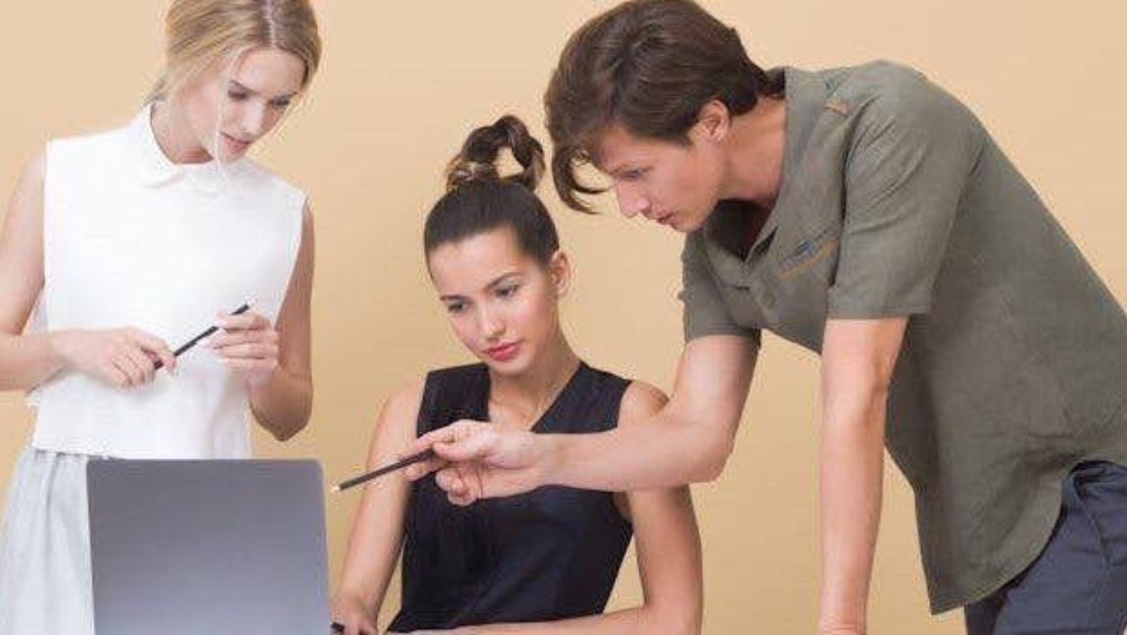 Three people looking at the laptop. 