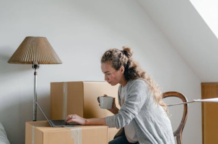 Woman looking at her laptop while surrounded by cardboard boxes