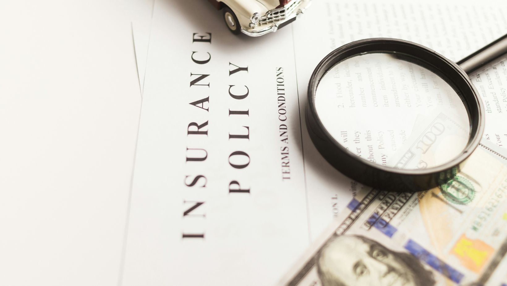 Insurance policy certificate with a car and dollar bills on top of it